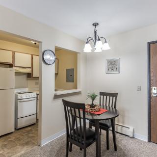 A cozy dining area with a small table and chairs adjacent to the kitchen, featuring modern decor and lighting.
