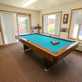 A well-lit game room featuring a pool table with balls racked for playing.
