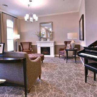 A cozy living room with elegant furnishings, featuring a piano and a fireplace.