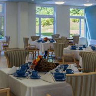 A bright dining room with neatly arranged tables and blue tableware.