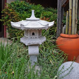 A serene Japanese garden featuring a stone lantern surrounded by lush greenery and bamboo.