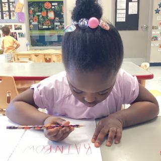 A young child focused on drawing in a classroom setting.