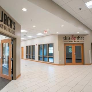 A corridor in a shopping center featuring storefront entrances.