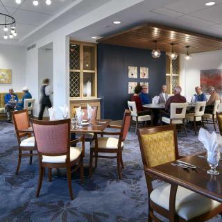 A modern restaurant dining area with elegantly set tables and patrons enjoying their meals.
