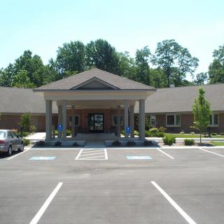 Image of a building with a covered entrance, featuring columns and an adjacent parking lot.