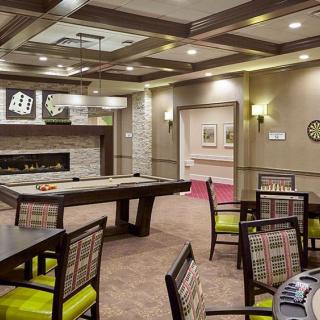 A modern game room featuring a shuffleboard table, comfortable seating, and elegant lighting.