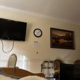 A cozy interior space featuring a television, clock, and artwork.
