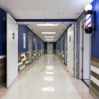 A clean and brightly lit hallway with multiple doors and a barber pole on the wall.