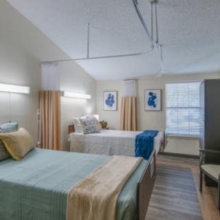 A hospital room with two neatly made beds, separated by curtains, providing a comfortable and orderly environment for patients.