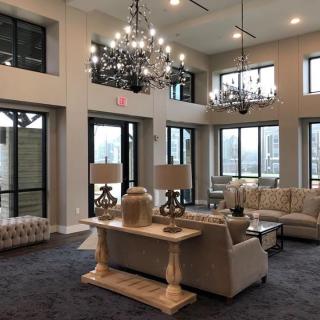 A luxurious living room featuring elegant chandeliers, ample natural light from large windows, and sophisticated furniture.