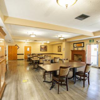 A spacious dining area with neatly arranged tables and chairs, illuminated by ceiling lights.