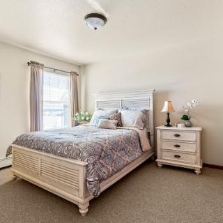 A cozy and elegantly designed bedroom featuring a comfortable bed, nightstand, and soft lighting.