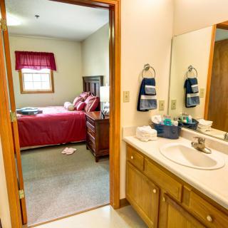 A cozy bedroom and bathroom setup with wooden furniture and a large mirror.