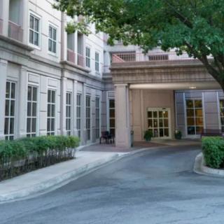 Building entrance with a driveway and surrounding greenery.