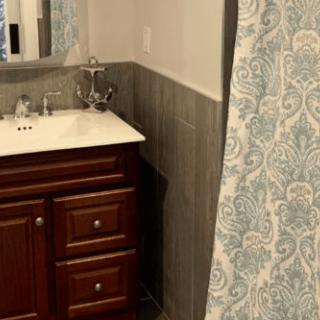 A bathroom featuring a sink with a wooden cabinet and patterned shower curtain.