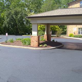 A view of the entrance to a building, featuring well-maintained landscaping and a paved driveway.