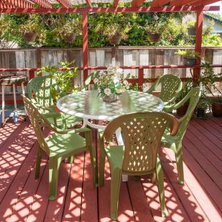 An outdoor patio with a round table and green chairs under a pergola.