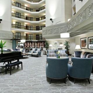 A luxurious hotel lobby featuring a grand piano, comfortable seating areas, and modern decor.