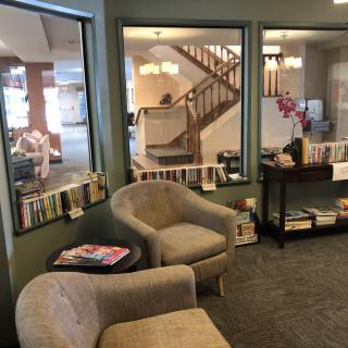 A cozy waiting area with comfortable chairs, a small table with magazines, and bookshelves in the background.
