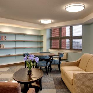 A cozy living room with a sofa, table, and bookshelf adorned with decorative items.