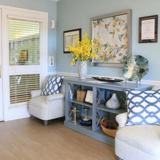 A cozy and modern living room with comfortable seating, decorative pillows, a stylish shelving unit, and vibrant floral arrangements.