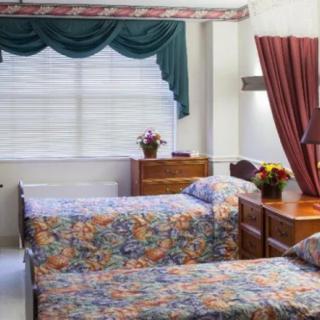 A bedroom with twin beds featuring floral bedding, a dresser, and decorative curtains.