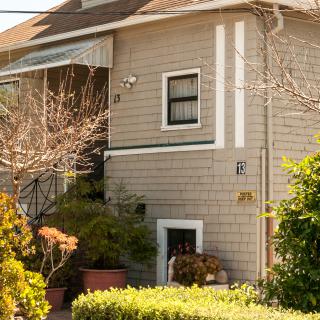 A charming residential house with a lush garden on a sunny day.