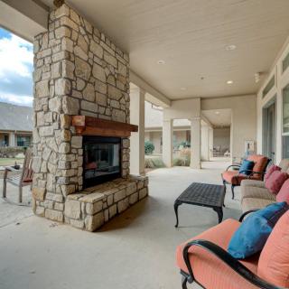 A cozy covered patio with cushioned seating and a stone fireplace.