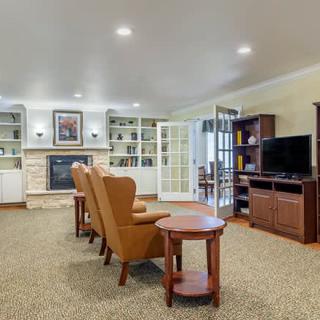 A cozy living room featuring comfortable armchairs, a fireplace, and a television setup with surrounding shelves.