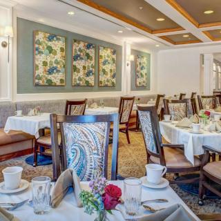 An elegant dining room with beautifully set tables and floral artwork on the walls.