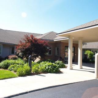 An inviting building entrance with neatly landscaped gardens and a covered walkway.