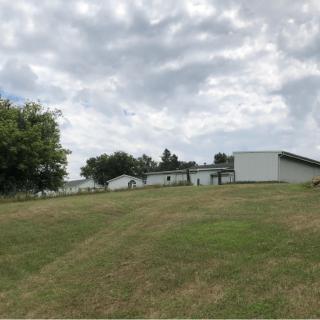 A grassy slope leading up to a group of buildings under a cloudy sky.