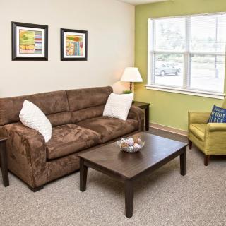 A cozy living room with a brown sofa, green armchair, and a wooden coffee table.