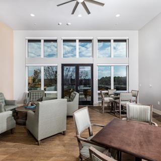 A modern living room featuring comfortable seating and large windows, illuminated by natural light.