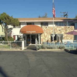 A small motel with a stone facade and orange awning over the entrance, surrounded by a paved parking lot.