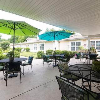 A cozy outdoor patio area featuring tables and chairs with colorful umbrellas, set amidst a lush garden backdrop.