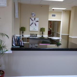 A tidy office reception area with a desk, plants, and wall decor.