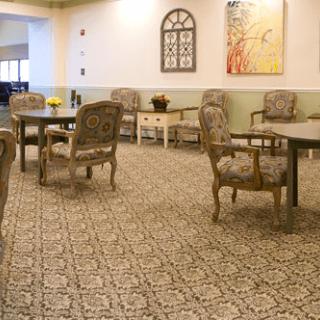 A cozy dining area with patterned carpet, elegant chairs, and decorative wall art.