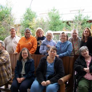 A group of people sitting and standing outdoors, posing for a photo.