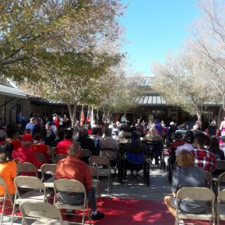 A large crowd gathered outdoors for a formal event under clear blue skies.