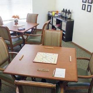 A cozy game room features tables with Scrabble boards and a coffee station.