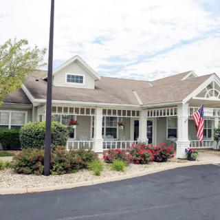 A residential building with an American flag in front, surrounded by landscaping and a driveway.