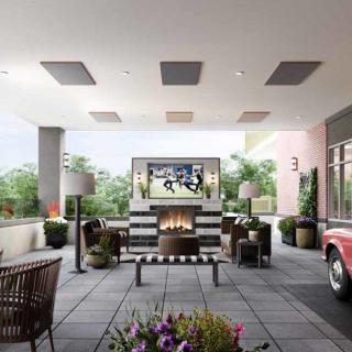 A modern outdoor patio with comfortable seating, a large fireplace, and a television for entertainment.