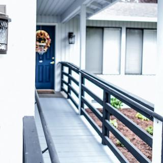A house entrance with a ramp leading to a blue front door decorated with a wreath.