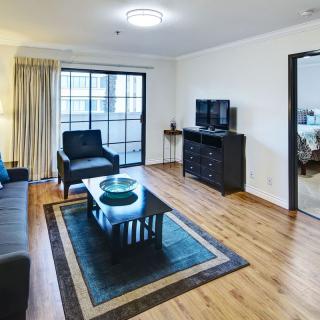 A modern living room with wooden flooring, featuring a sofa, coffee table, and television.