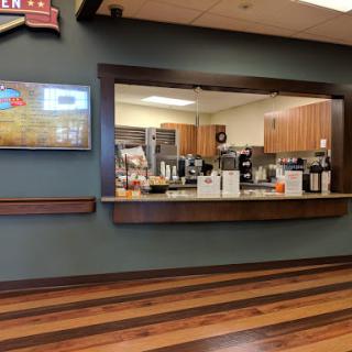 A cozy cafe interior showcasing a well-equipped kitchen with wooden flooring and modern decor.