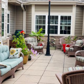 A cozy patio with wicker furniture and colorful cushions surrounded by potted plants.