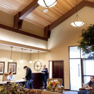 A modern reception area with people interacting at a desk and others seated in the waiting area.
