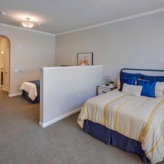 A spacious bedroom featuring a double bed with blue and beige bedding, separated by a partial wall.