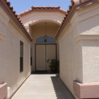 A walkway leading to the entrance of a residential house with an arched roof.